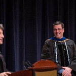 Faculty Member smiles as he listens to a fellow faculty member give remarks